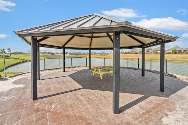 view of patio featuring a water view, fence, and a gazebo