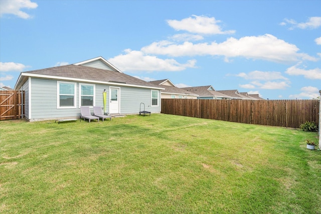 back of property with a fenced backyard and a yard