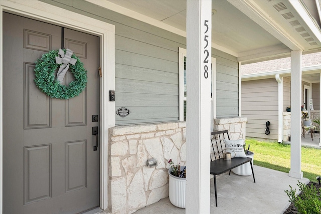 property entrance featuring stone siding and a porch