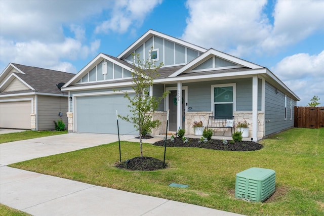 craftsman inspired home with covered porch, driveway, stone siding, a front lawn, and board and batten siding