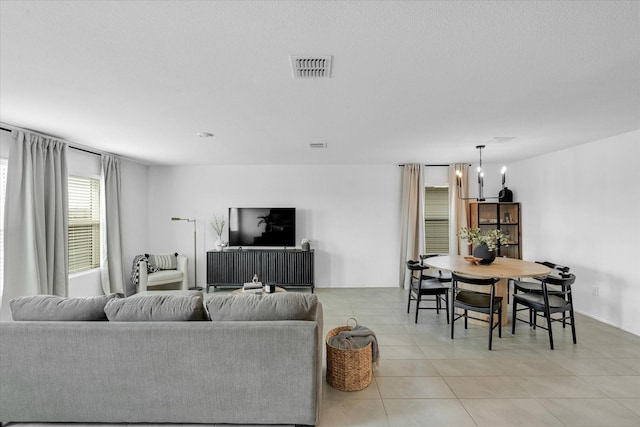 living room with a chandelier, visible vents, and light tile patterned floors