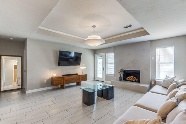 living room featuring light tile patterned flooring, ornamental molding, and a tray ceiling