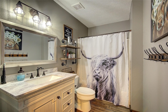 bathroom featuring hardwood / wood-style flooring, vanity, walk in shower, toilet, and a textured ceiling