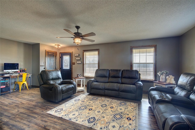 living room featuring dark wood-type flooring, a wealth of natural light, a textured ceiling, and ceiling fan