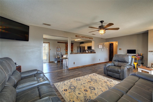 living room featuring ceiling fan, a textured ceiling, and dark hardwood / wood-style flooring