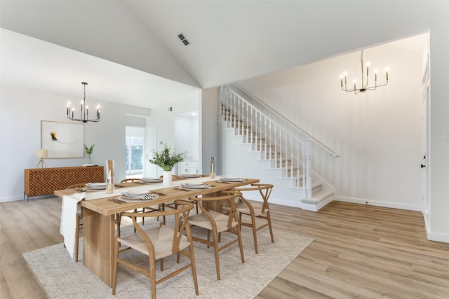 dining room with a chandelier, high vaulted ceiling, and light wood-type flooring