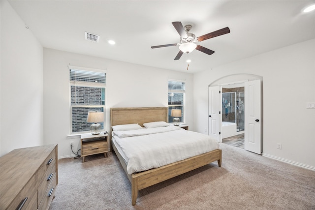 bedroom with ceiling fan, connected bathroom, and dark colored carpet