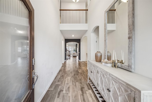 hallway featuring a towering ceiling and light hardwood / wood-style floors