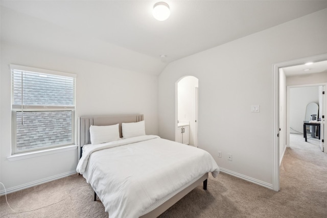 carpeted bedroom featuring vaulted ceiling and ensuite bathroom