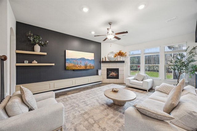 living room featuring hardwood / wood-style flooring, ceiling fan, and a tile fireplace