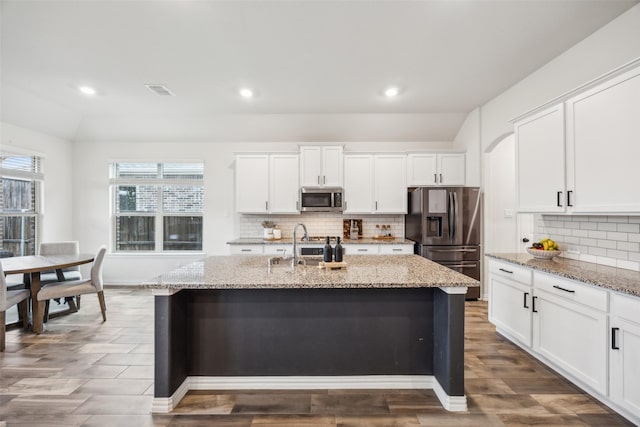 kitchen with a kitchen island with sink, white cabinetry, and stainless steel appliances