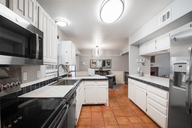 kitchen featuring appliances with stainless steel finishes, tile countertops, kitchen peninsula, and white cabinets