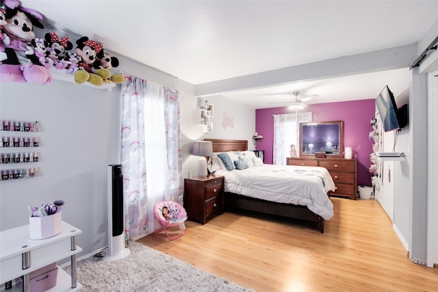 bedroom featuring ceiling fan, a barn door, and light wood-type flooring