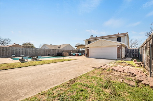 exterior space featuring central AC unit, a garage, and a fenced in pool