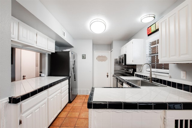 kitchen with tile countertops, kitchen peninsula, and appliances with stainless steel finishes