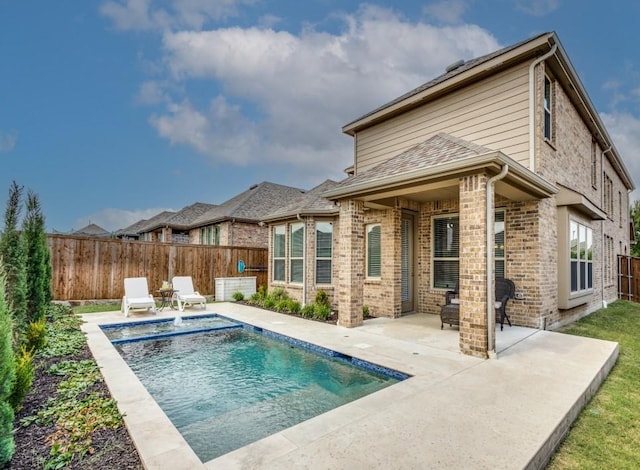 back of property with pool water feature, a fenced in pool, and a patio area