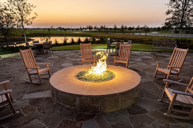 patio terrace at dusk with a water view and an outdoor fire pit