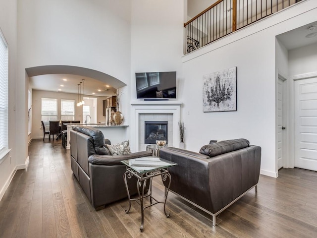 living room featuring a tile fireplace, wood-type flooring, and a towering ceiling