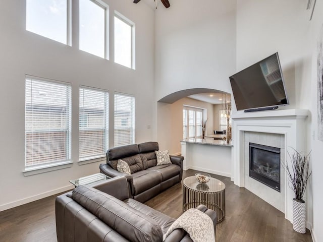 living room with dark hardwood / wood-style flooring, a fireplace, ceiling fan, and a high ceiling