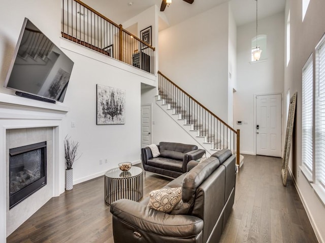 living room with a towering ceiling, dark wood-type flooring, and a tile fireplace