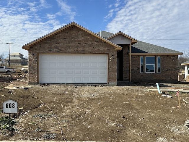 ranch-style house with an attached garage, brick siding, and a shingled roof