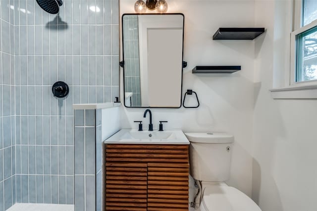 bathroom featuring vanity, tiled shower, and toilet