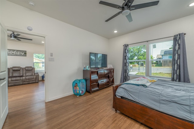 bedroom featuring hardwood / wood-style flooring, ceiling fan, and multiple windows