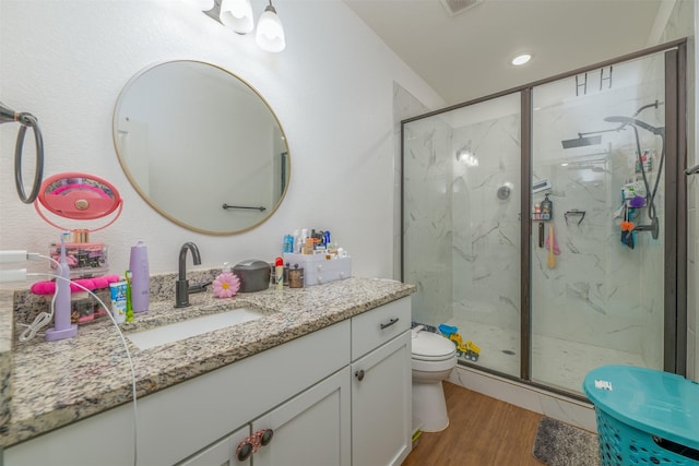 bathroom featuring toilet, vanity, a shower with door, and hardwood / wood-style floors