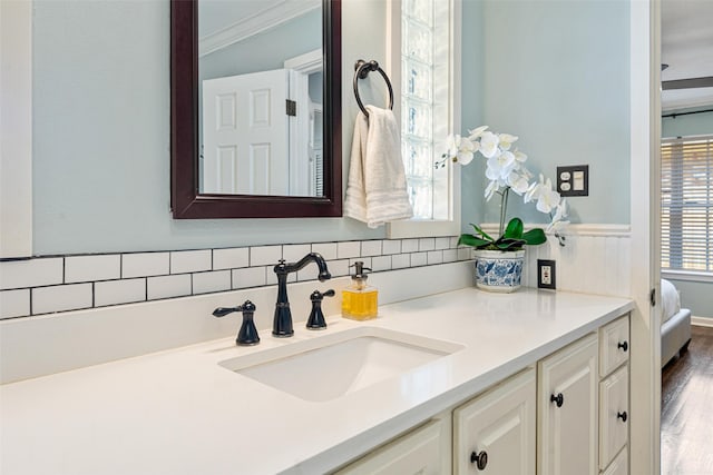 bathroom featuring vanity, crown molding, and decorative backsplash