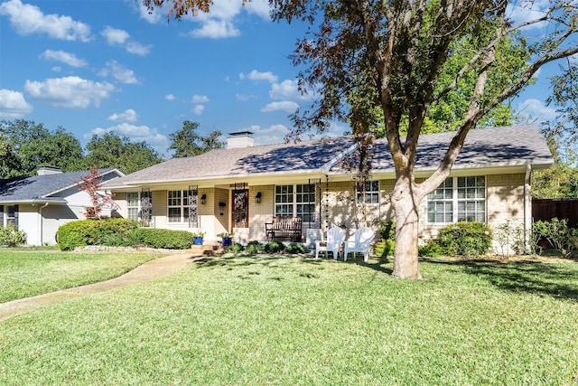 ranch-style house featuring covered porch and a front lawn