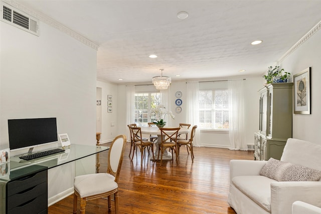 dining space with ornamental molding, hardwood / wood-style floors, and a notable chandelier