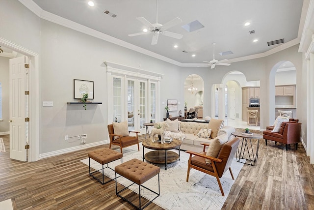 living room with hardwood / wood-style flooring, ornamental molding, ceiling fan with notable chandelier, and french doors