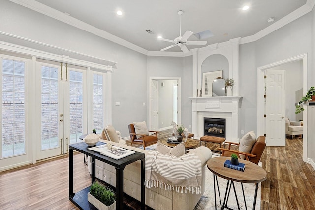 living room with french doors, ornamental molding, wood finished floors, and a glass covered fireplace