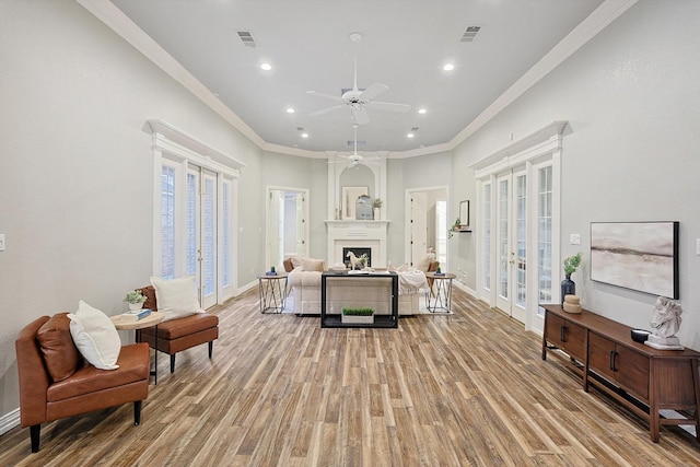 living room with ornamental molding, ceiling fan, light wood-type flooring, and french doors