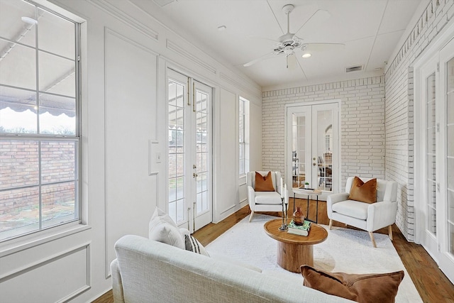 living area with french doors, visible vents, dark wood finished floors, and brick wall