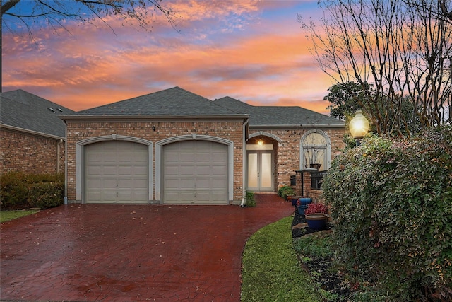 view of front of property with a garage, decorative driveway, brick siding, and a shingled roof