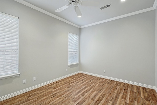 unfurnished room featuring ornamental molding, wood finished floors, visible vents, and baseboards