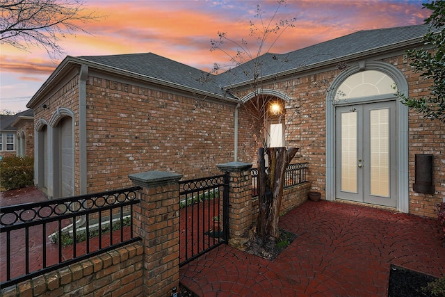 patio terrace at dusk featuring an attached garage and french doors