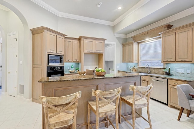 kitchen featuring stainless steel appliances, light brown cabinetry, stone countertops, and light tile patterned floors