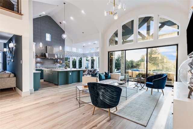 living room featuring high vaulted ceiling, a notable chandelier, plenty of natural light, and light wood finished floors
