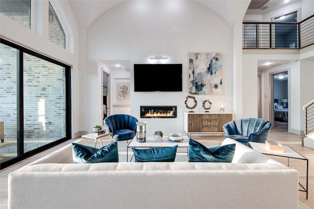 living area with wood finished floors, a wealth of natural light, and a glass covered fireplace