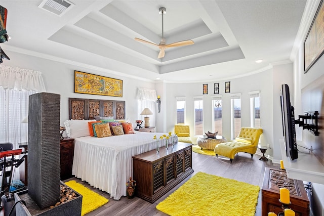 bedroom featuring a tray ceiling, hardwood / wood-style floors, crown molding, and ceiling fan