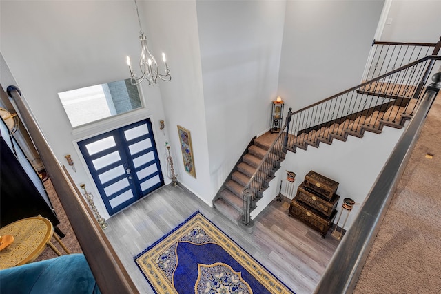 foyer entrance with wood-type flooring, a chandelier, and a high ceiling