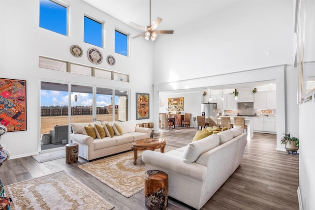 living room featuring hardwood / wood-style flooring, ceiling fan, and a high ceiling