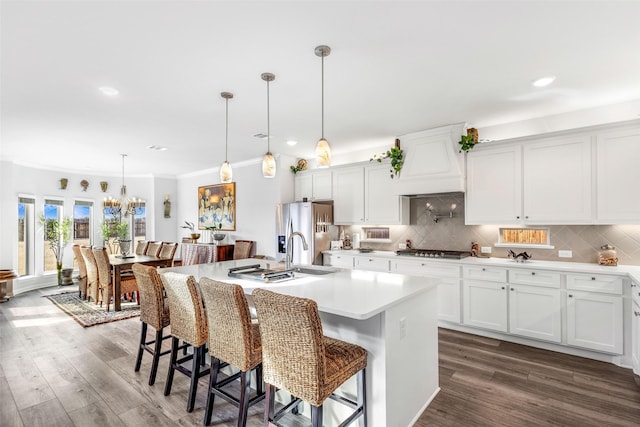 kitchen featuring hanging light fixtures, a kitchen island with sink, a breakfast bar area, and white cabinets