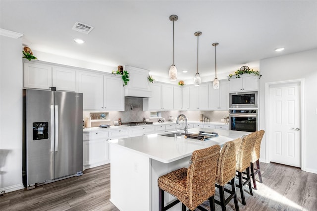 kitchen featuring pendant lighting, sink, appliances with stainless steel finishes, an island with sink, and white cabinets