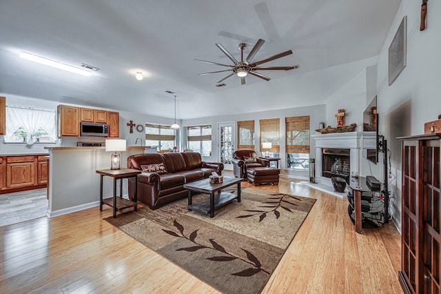 living room featuring ceiling fan, vaulted ceiling, and light wood-type flooring