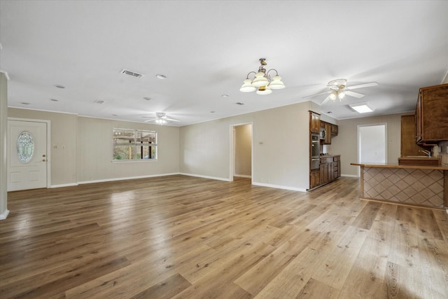 unfurnished living room with ceiling fan with notable chandelier and light wood-type flooring