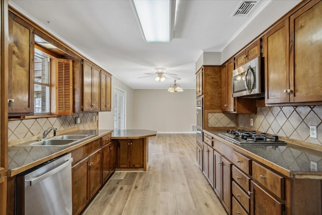 kitchen with tasteful backsplash, appliances with stainless steel finishes, sink, and light hardwood / wood-style floors