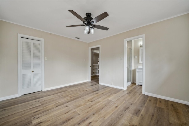 unfurnished bedroom featuring connected bathroom, ornamental molding, a closet, ceiling fan, and light hardwood / wood-style floors